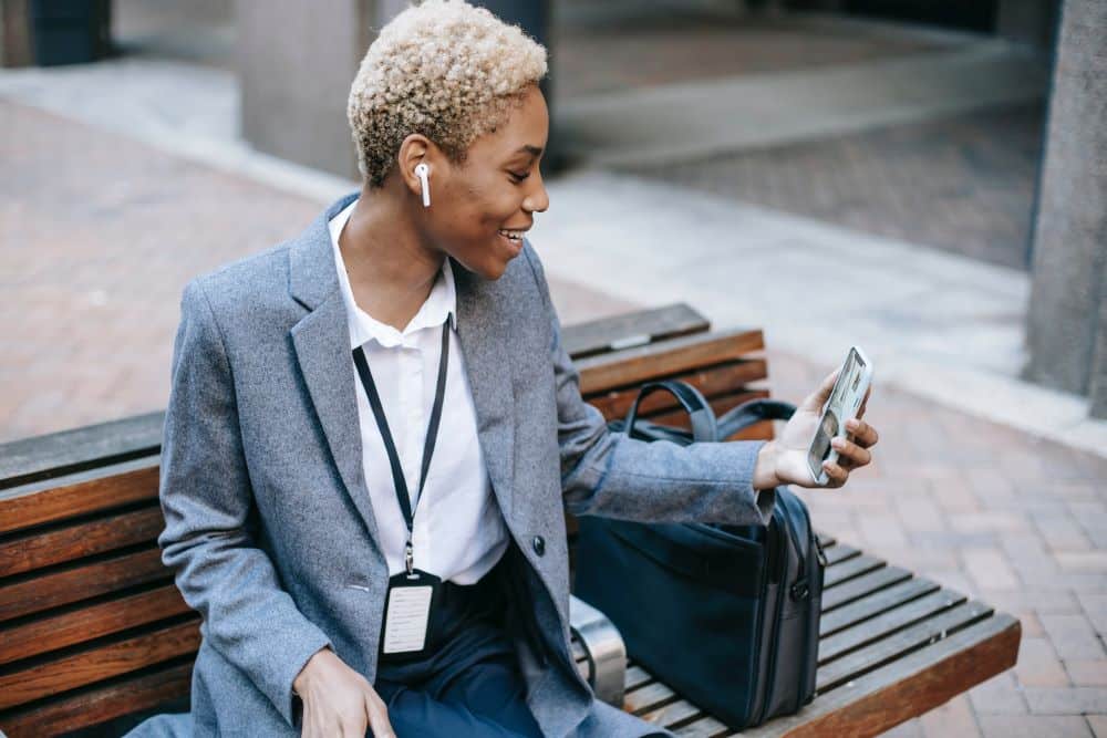 A depiction of true happiness in the corporate world - woman sitting on bench video calling her loved ones