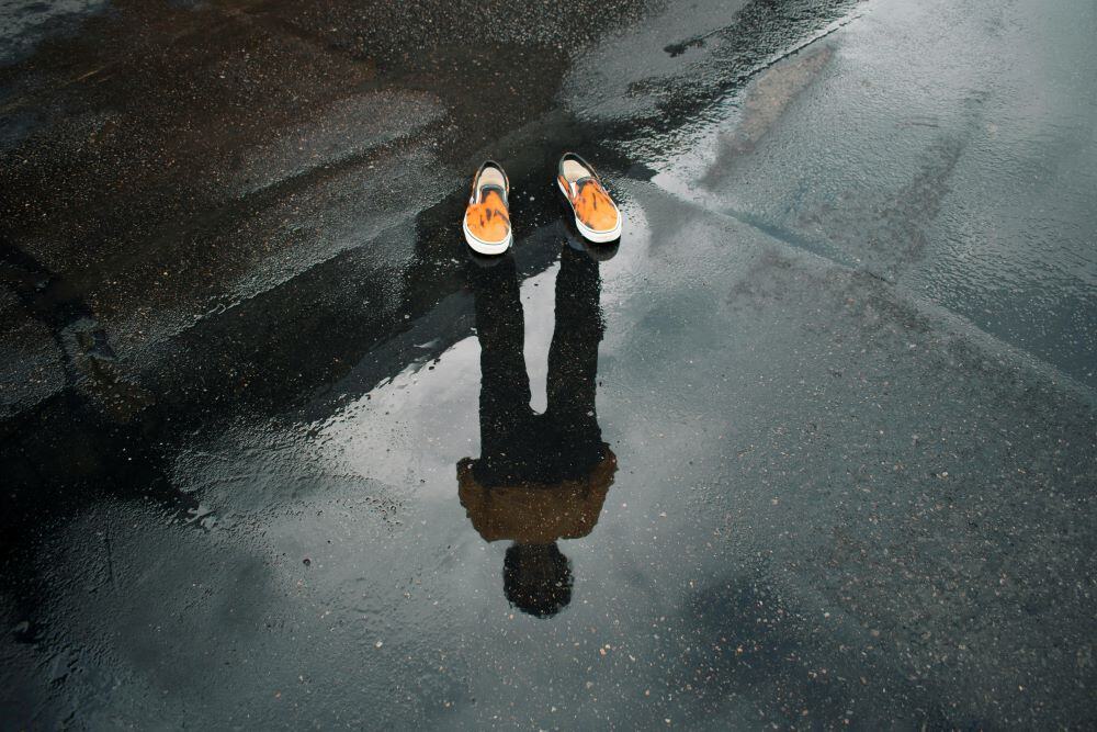 A guys reflection in a puddle representing personal growth