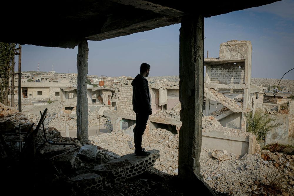 Guy over looks a war torn town, evaluating the psychological roots of conflict